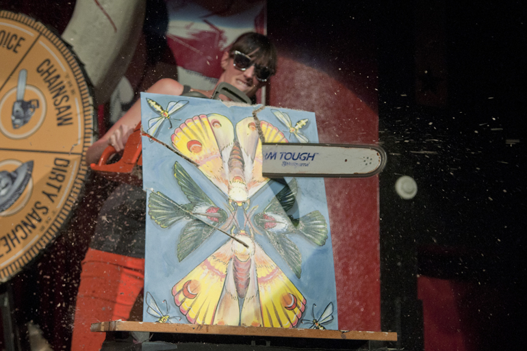Primary Colours board member Naomi Spier slices through a painting with a chainsaw during the Art vs. Art competition at The Vogue in Broad Ripple, Friday, Sept. 27, 2013.