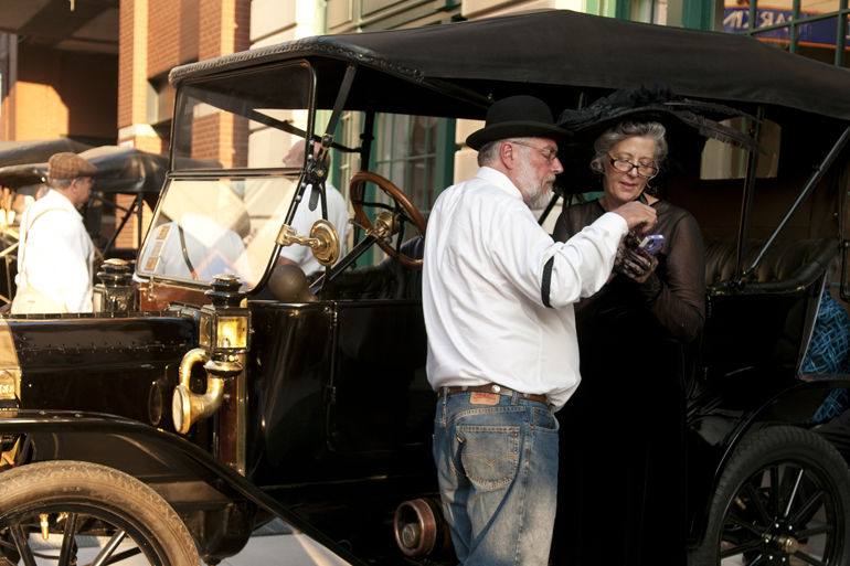 Evan Cork and Deborah Magga try to solve a problem on her iPhone while in their period clothing during the Omni Severin Hotel\'s 100th anniversary party on Georgia Street, Friday, August 23, 2013.
