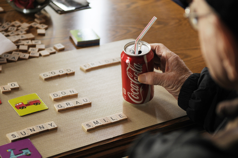 Don Grau, who has Alzheimer\'s disease, picks up his drink and looks at Scrabble letters arranged on his placemat on Friday, March 29, 2013, at his daughter-in-law\'s home in West Lafayette. During visits from IU Health Arnett\'s Charmin Smith in the Aging Brain Care program, Grau spells words, identifies figures on cards, and talks with Smith and his caregiver, daughter-in-law Peggy Grau.