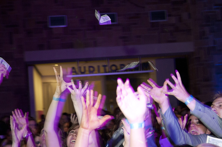 Students reach for fake money thrown into the air during Perry Meridian High School\'s prom, themed \