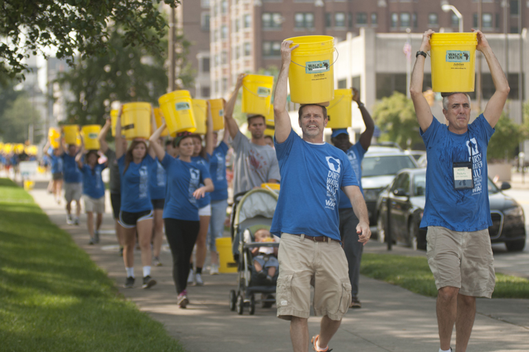 Rick Grover (front left) leads walkers north along Meridian Street with Mike Peduto of Jubilee Village Project during the third annual Walk for Water event downtown, Saturday, Aug. 2, 2014. The event raised money for a community clean-water well in Kager, Kenya. Attendees walked from American Legion Mall to the canal, filled buckets with water and walked back to the mall, simulating the path villagers without clean water have to take every day.