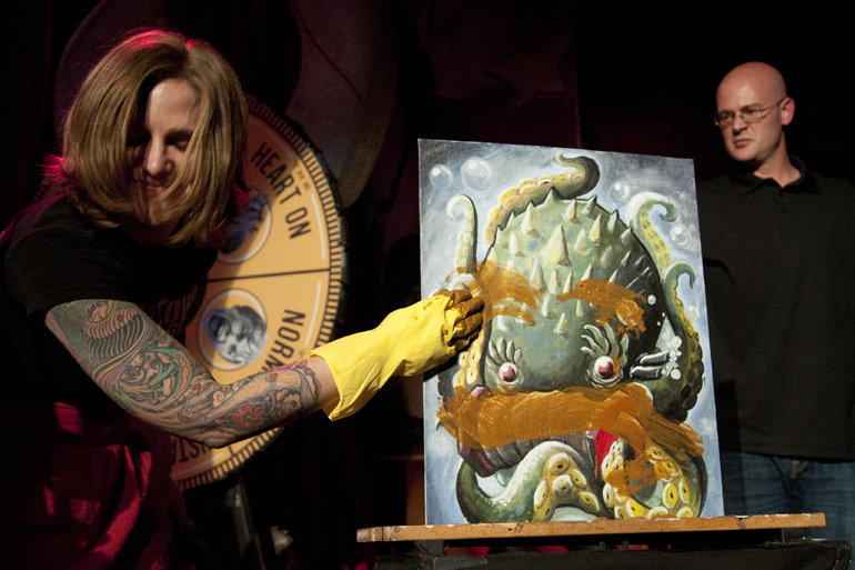 A member of the Naptown Roller Girls cringes as she wipes feces on a painting during the Art vs. Art competition at The Vogue in Broad Ripple, Friday, Sept. 27, 2013.