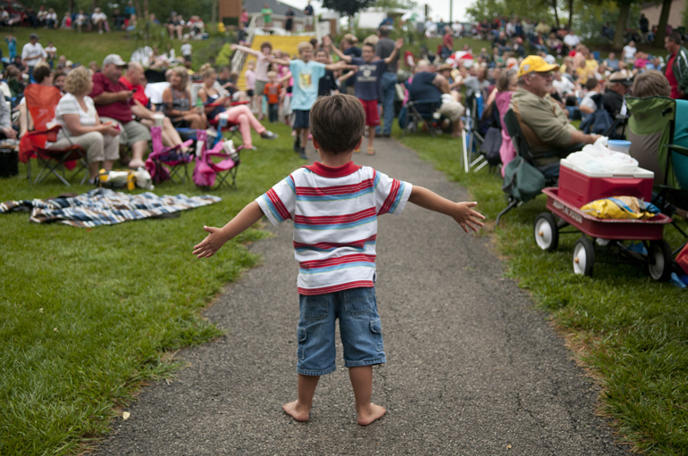 Joshua Wilson, 3, stands in the way of dancing children marching down a path during a Greenwood Summer Concert Series event on Saturday, July 20, 2013, at the Greenwood Amphitheater in Greenwood, Ind.
