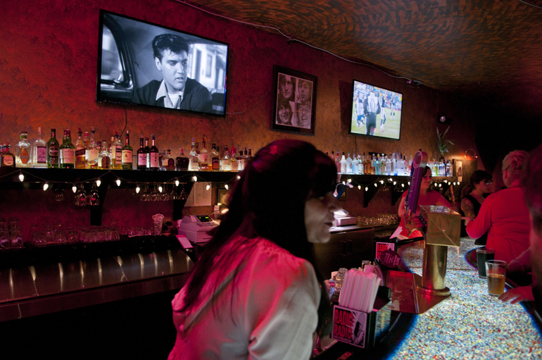 An old Elvis Presley movie and the Colts-Patriots games play on TVs behind the bar during the 10th annual Elvis Birthday Bash at Radio Radio in Fountain Square, Saturday, Jan. 11, 2014.