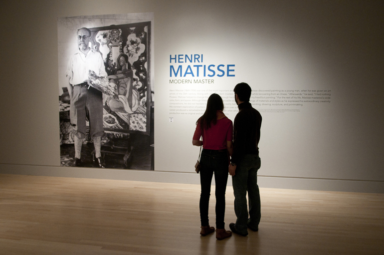 Chelsea van der Meer and Giorgio Giudice stand together looking at a photo of artist Henri Matisse at Last Call for the \