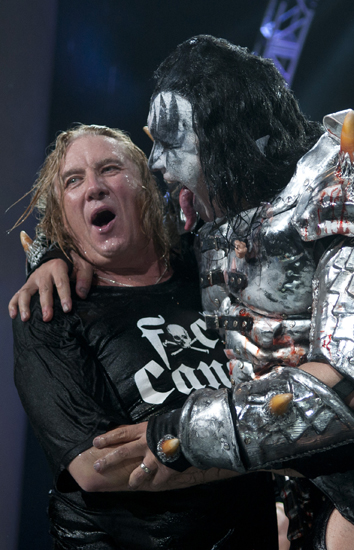 Rick Savage of Def Leppard avoids the tongue of Gene Simmons of KISS after the bands performed the ALS ice bucket challenge at Klipsch Music Center, Friday, Aug. 22, 2014. The bands each pledged $10,000 to the ALS Association and challenged music acts such as Elton John, U2 and Prince.