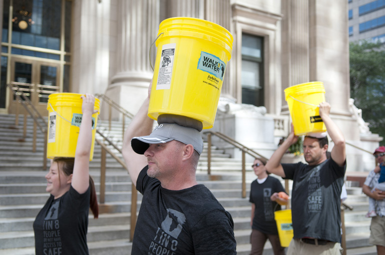 Joe Locke and others walk their water buckets back to American Legion Mall during the Walk for Water 5K event downtown, Saturday, July 27, 2013.