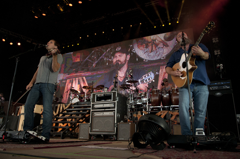 Zac Brown Band fiddler Jimmy De Martini and guitarist John Driskell Hopkins play in front of a giant screen showing vocalist Zac Brown at Klipsch Music Center, Sunday, July 13, 2014.